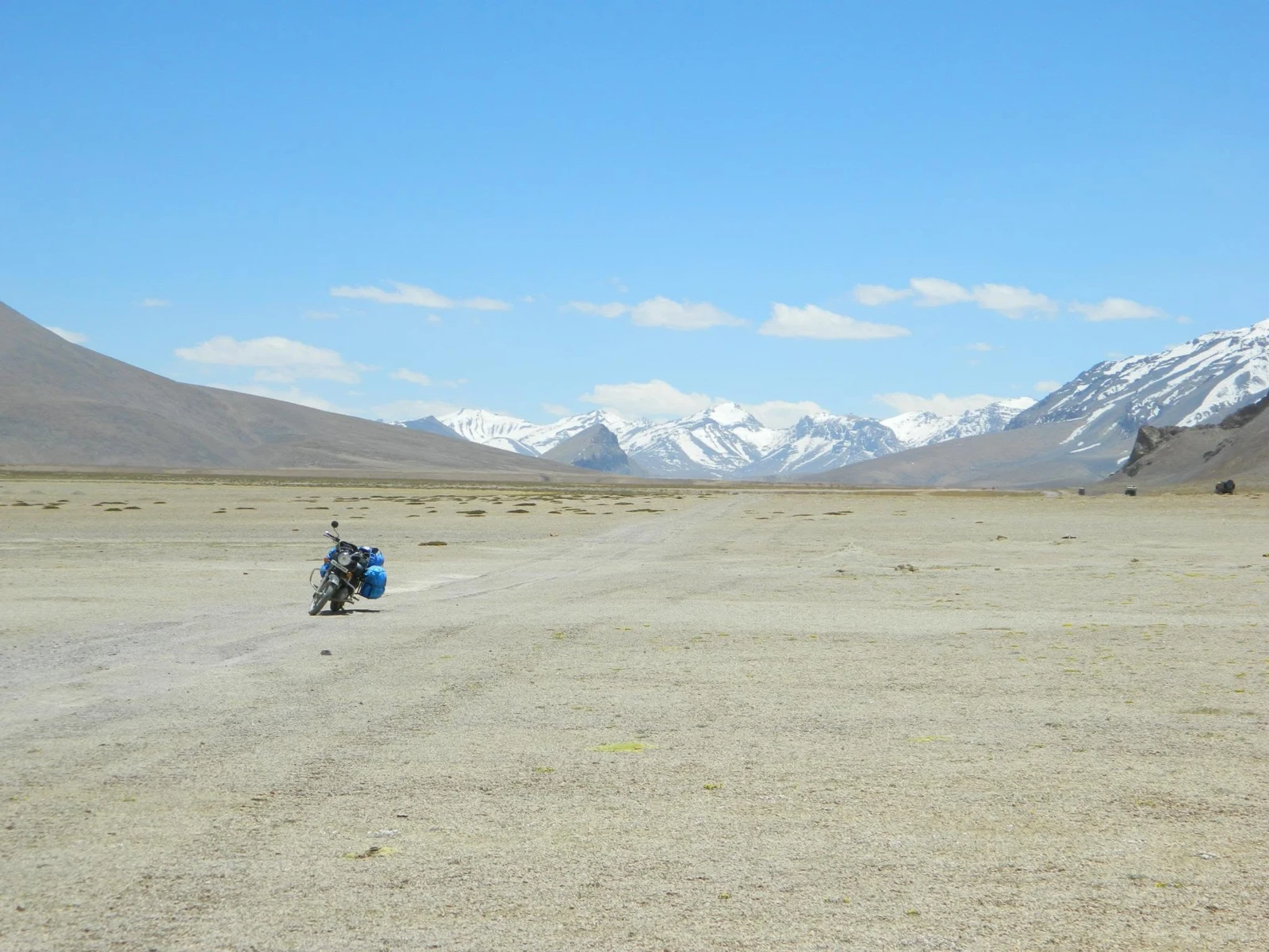 A small motorcycle rider in a vast mountain plain